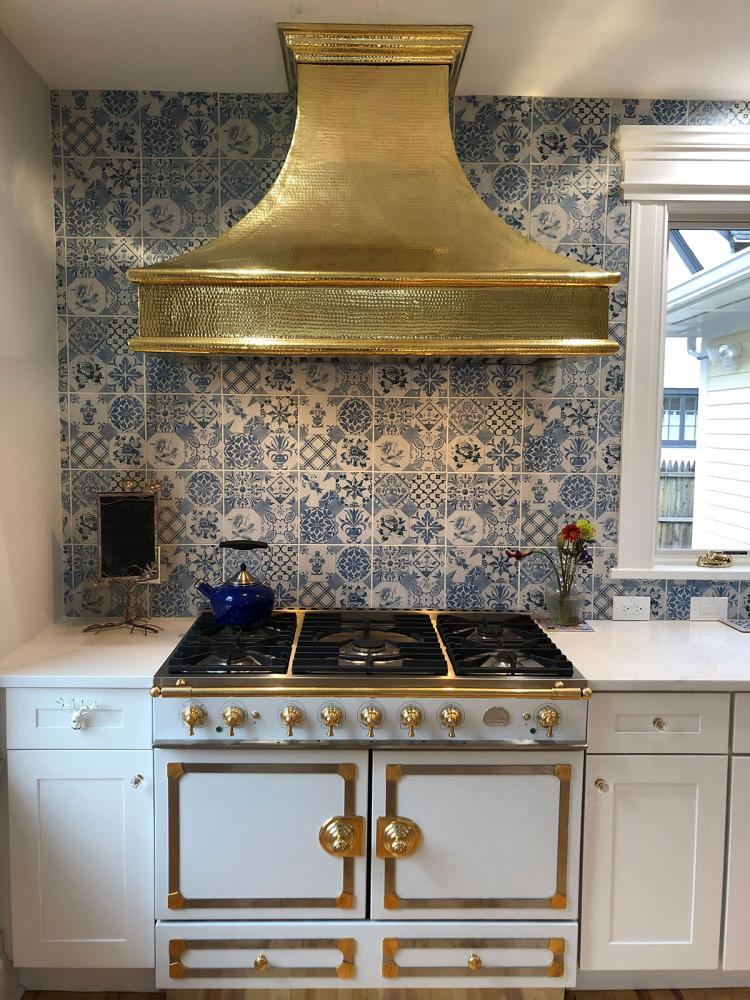 Brass kitchen hood, marble slab backsplash, navy blue kitchen